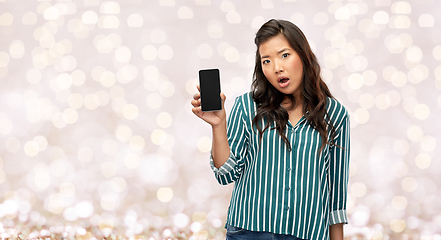 Image showing shocked asian woman with smartphone over lights