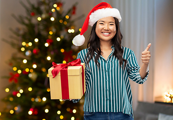 Image showing asian woman with christmas gift showing thumbs up