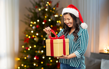 Image showing happy asian woman opening christmas gift at home