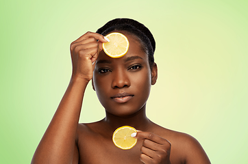 Image showing african woman making eye mask of lemons