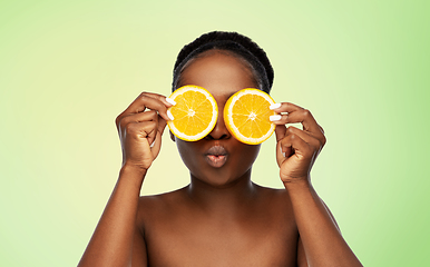 Image showing african woman making eye mask of oranges