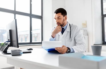 Image showing stressed male doctor with clipboard at hospital