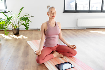 Image showing woman with tablet pc meditating at yoga studio