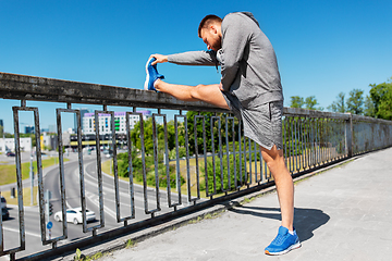 Image showing man stretching leg on bridge