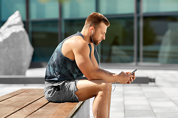 Image showing young athlete man with earphones and smartphone