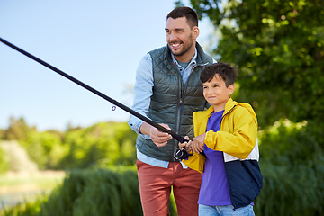 Image showing happy smiling father and son fishing on river