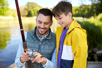 Image showing happy smiling father and son fishing on river