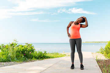 Image showing young african american woman stretching on beach