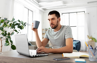 Image showing man with laptop drinking coffee at home office