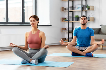 Image showing couple meditating in yoga lotus pose at home