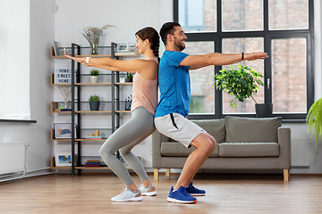 Image showing happy couple exercising and doing squats at home