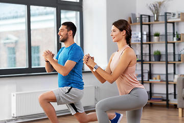 Image showing happy couple exercising and doing squats at home
