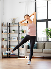 Image showing smiling young woman exercising at home