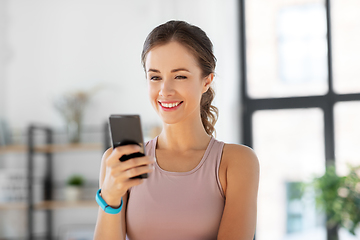 Image showing young woman with smatphone exercising at home