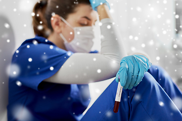 Image showing sad doctor or nurse holding beaker with blood test