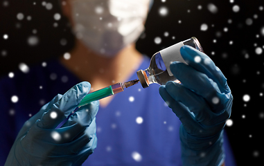 Image showing doctor in face mask with syringe and medicine