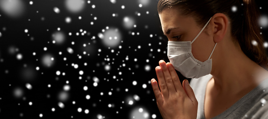 Image showing sick young woman in protective face mask praying