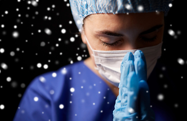 Image showing female doctor or nurse in face mask praying