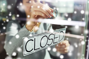 Image showing woman hanging banner with closed word on door