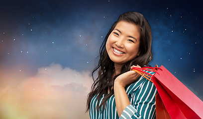 Image showing happy asian woman with shopping bags on night sky