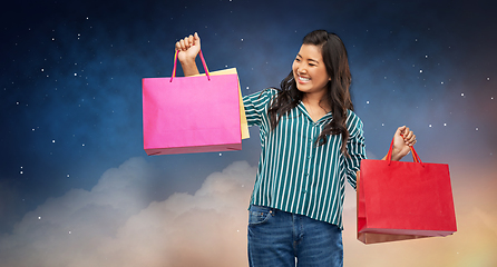 Image showing happy asian woman with shopping bags on night sky