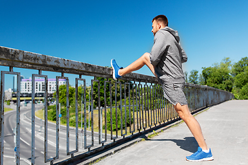 Image showing man stretching leg on bridge