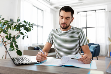 Image showing man with papers and laptop working at home office