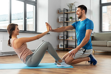 Image showing woman with personal trainer doing sit ups at home