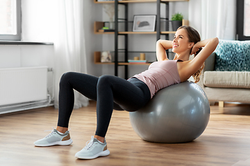 Image showing happy woman exercising on fitness ball at home