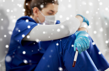 Image showing sad doctor or nurse holding beaker with blood test