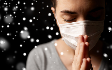 Image showing sick young woman in protective face mask praying