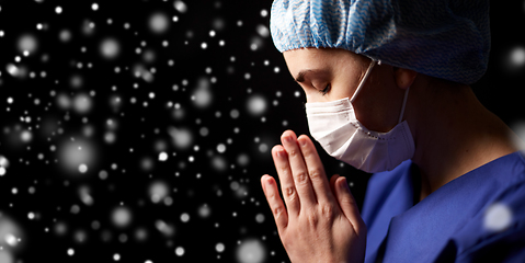 Image showing female doctor or nurse in face mask praying