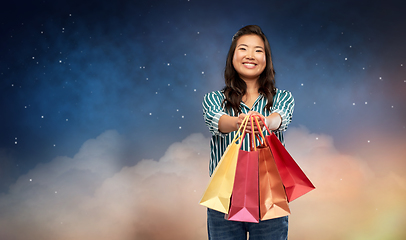 Image showing happy asian woman with shopping bags on night sky