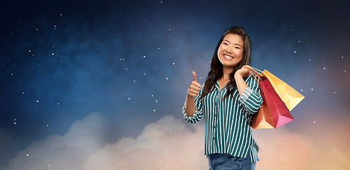 Image showing asian woman with shopping bags showing thumbs up