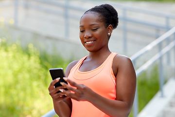 Image showing sporty african woman using smartphone in city