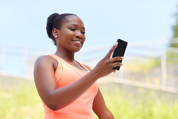 Image showing sporty african woman using smartphone outdoors