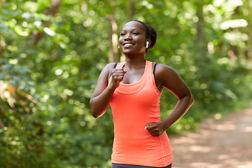 Image showing happy african woman in earphones running in park