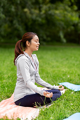 Image showing young asian woman meditating at summer park