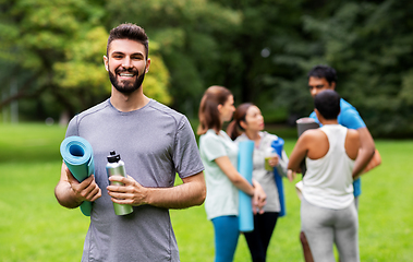 Image showing smiling man with yoga mat over group of people