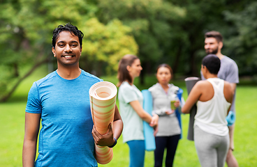 Image showing smiling man with yoga mat over group of people