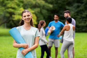 Image showing smiling woman with yoga mat over group of people