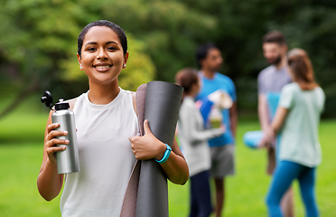 Image showing smiling woman with yoga mat and bottle at park