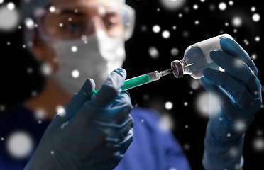 Image showing doctor in face mask with syringe and medicine