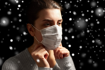 Image showing sick woman adjusting protective medical face mask