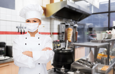 Image showing female chef in mask with crossed arms at kitchen