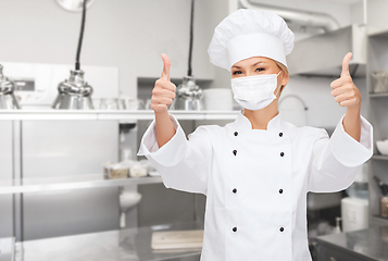 Image showing female chef in mask showing thumbs up at kitchen