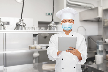 Image showing female chef in mask with tablet pc at kitchen