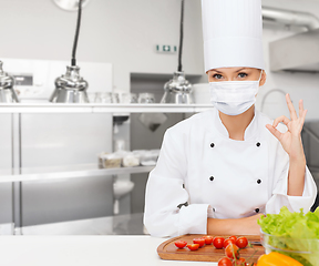 Image showing female chef in mask showing ok sign at kitchen