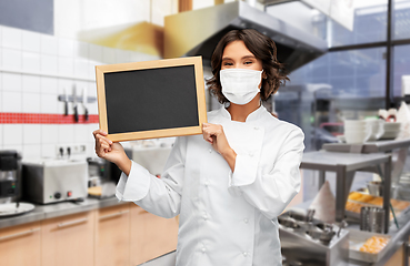 Image showing female chef in mask with chalkboard at kitchen