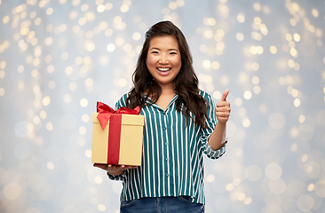 Image showing happy asian woman with gift box showing thumbs up